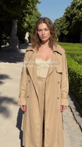 Model wearing beige maxi trench coat and matching wide-leg trousers outdoors