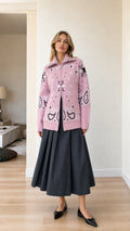 Front full view of woman wearing pink paisley jacquard zip-up knit cardigan with charcoal skirt