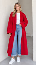 Front full-length view of model wearing a bright red oversized maxi coat with jeans and white sneakers