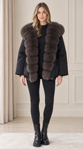Front view of model wearing black plush hooded winter parka coat with black leggings and boots