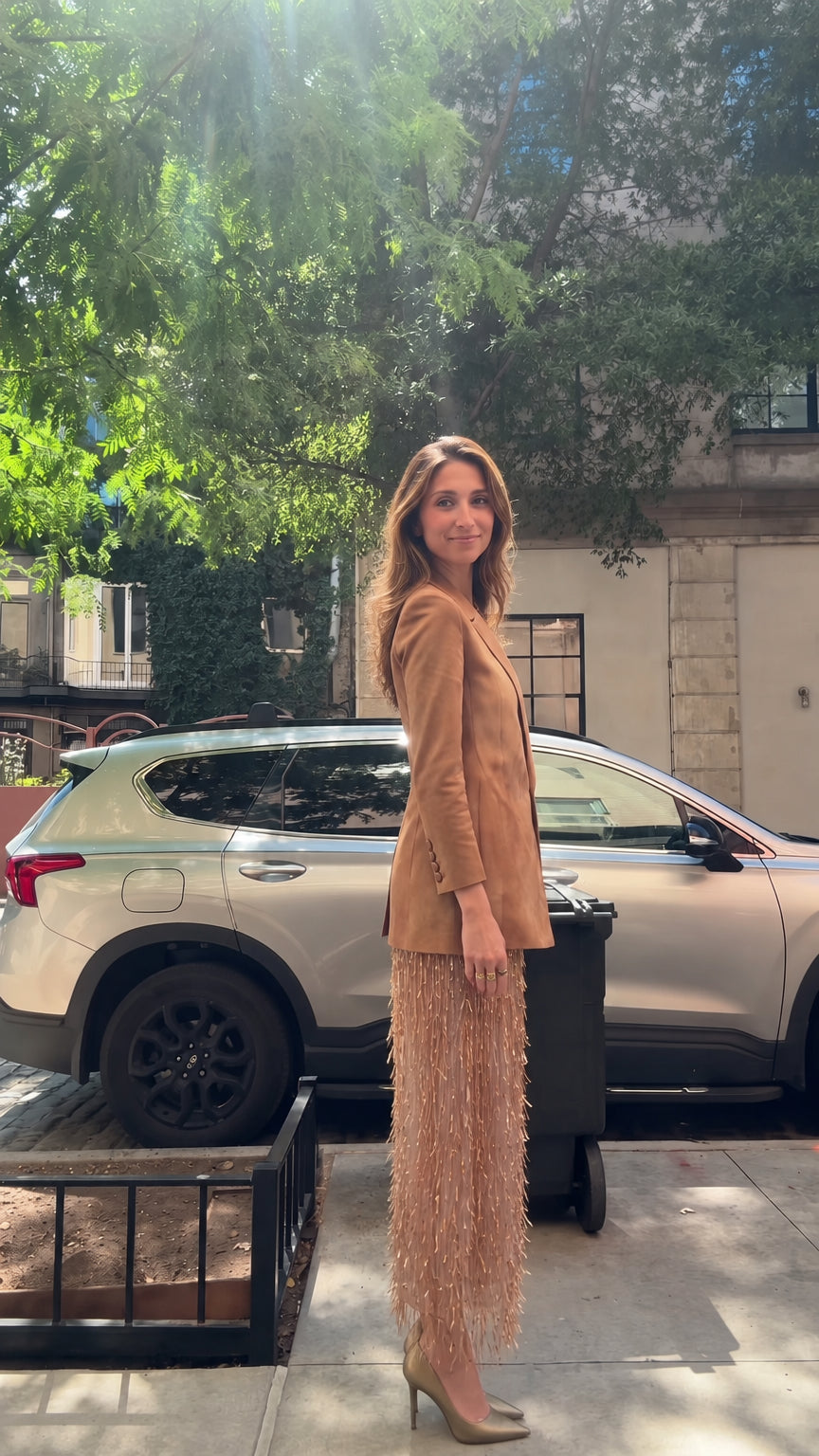 Side profile view of model in tailored tan blazer and cascading fringe skirt