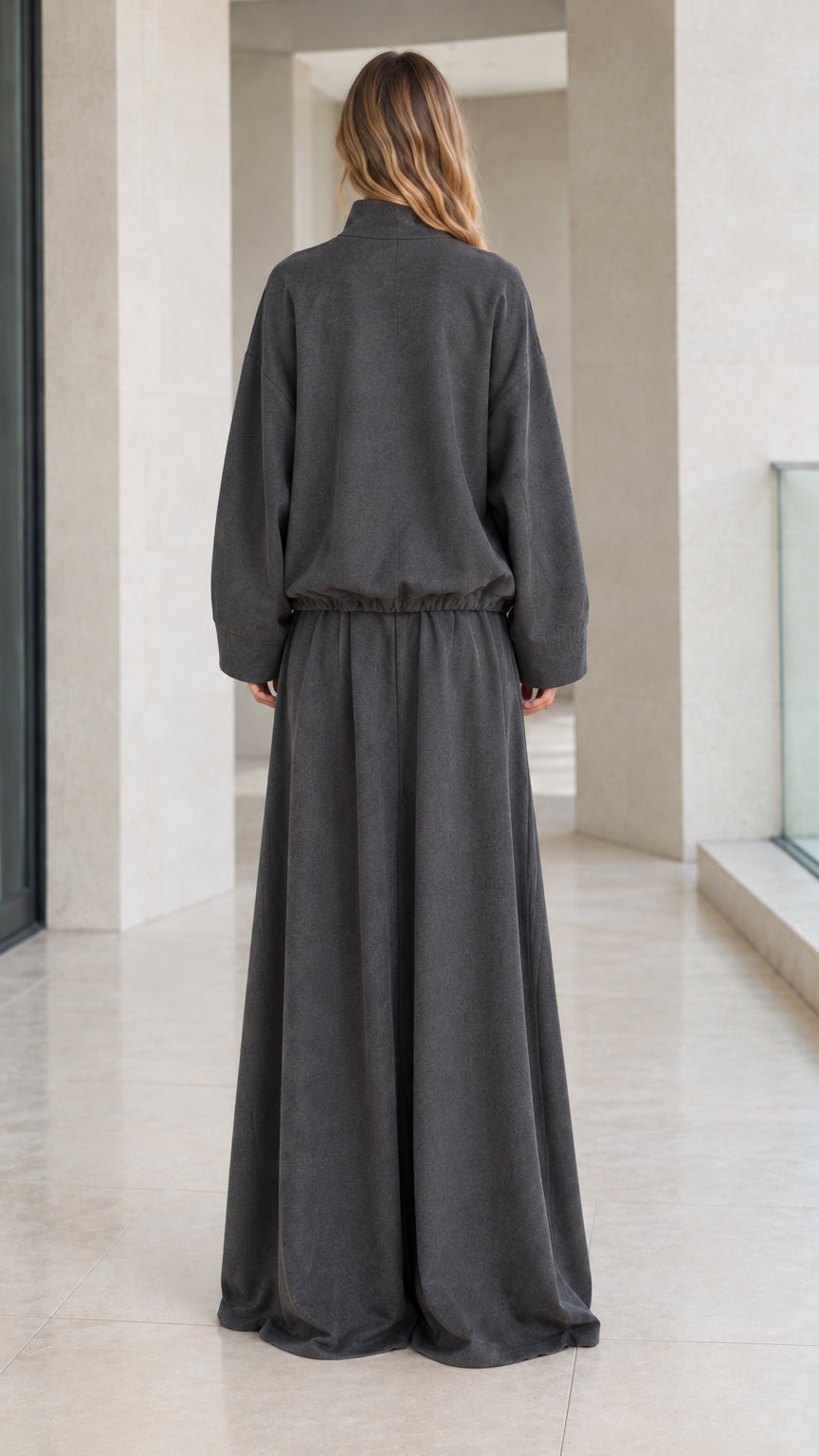 Back full view of woman wearing relaxed charcoal grey track jacket and wide-leg trousers