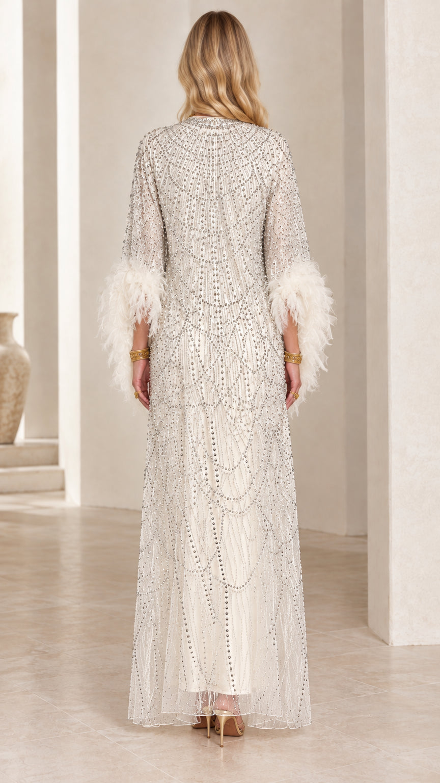 Back view of white beaded maxi gown featuring feather trim sleeves