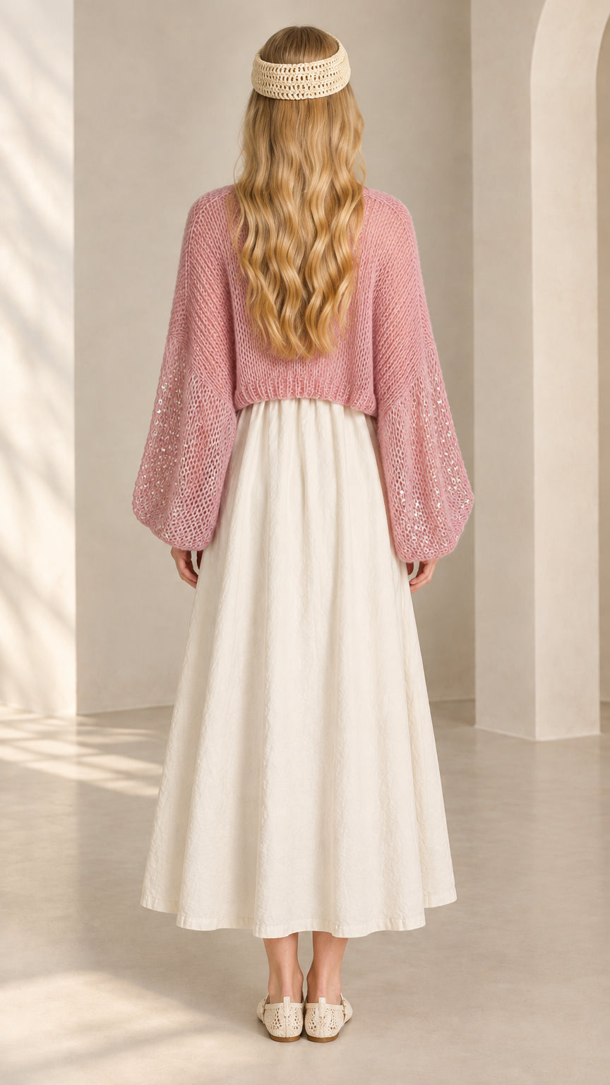 Back view of woman wearing pink open-knit cropped shrug cardigan