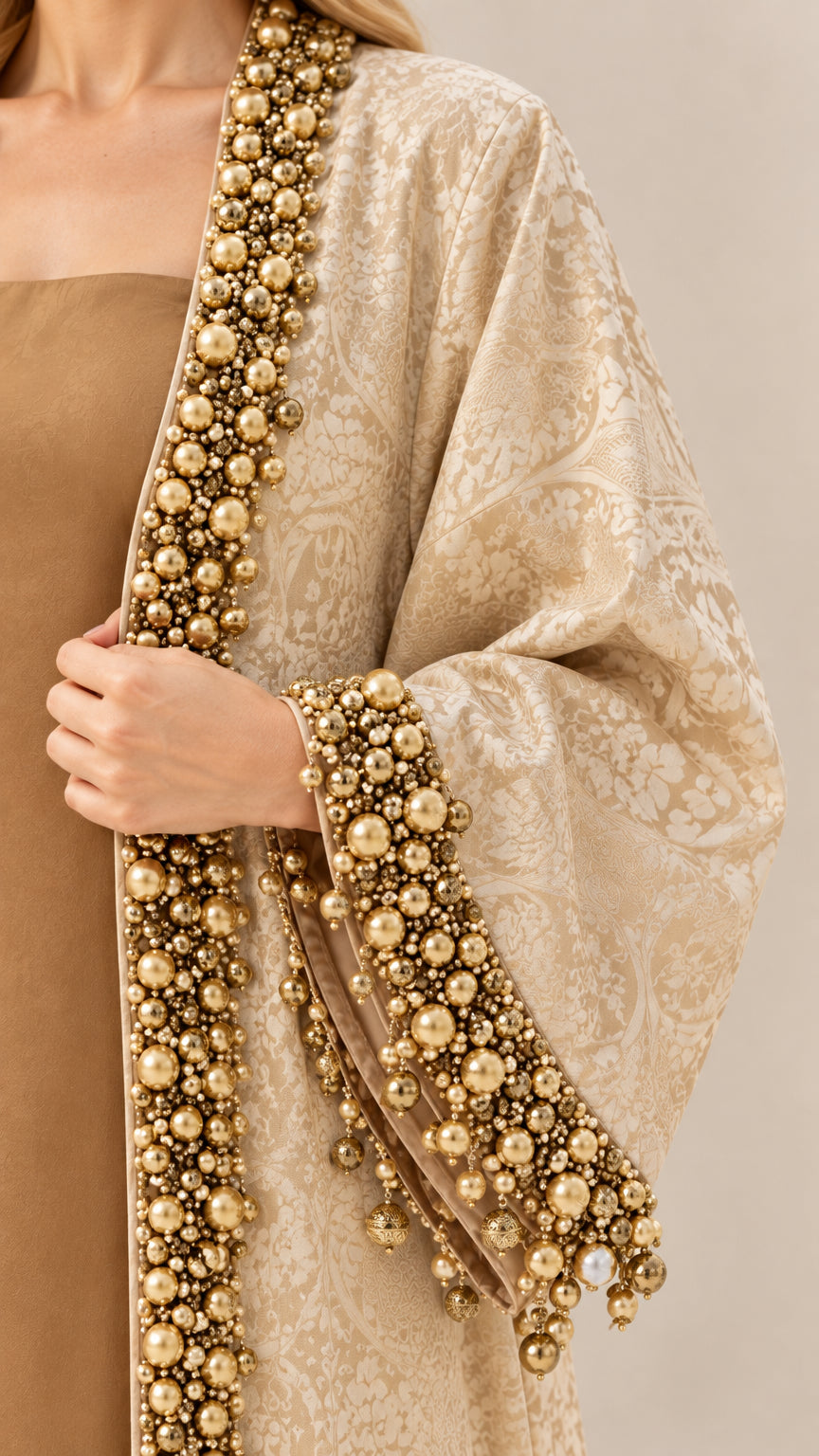Close-up detail of luxury gold beadwork and faux pearl trims on jacquard sleeve and front edge