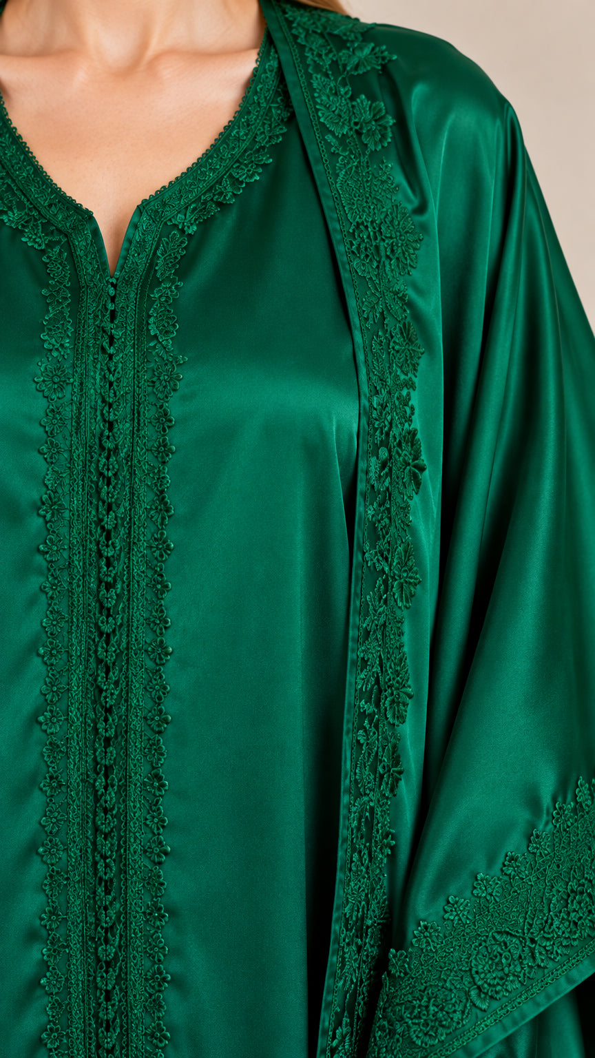 Close-up detail of embroidered V-neckline and trim on emerald green satin fabric