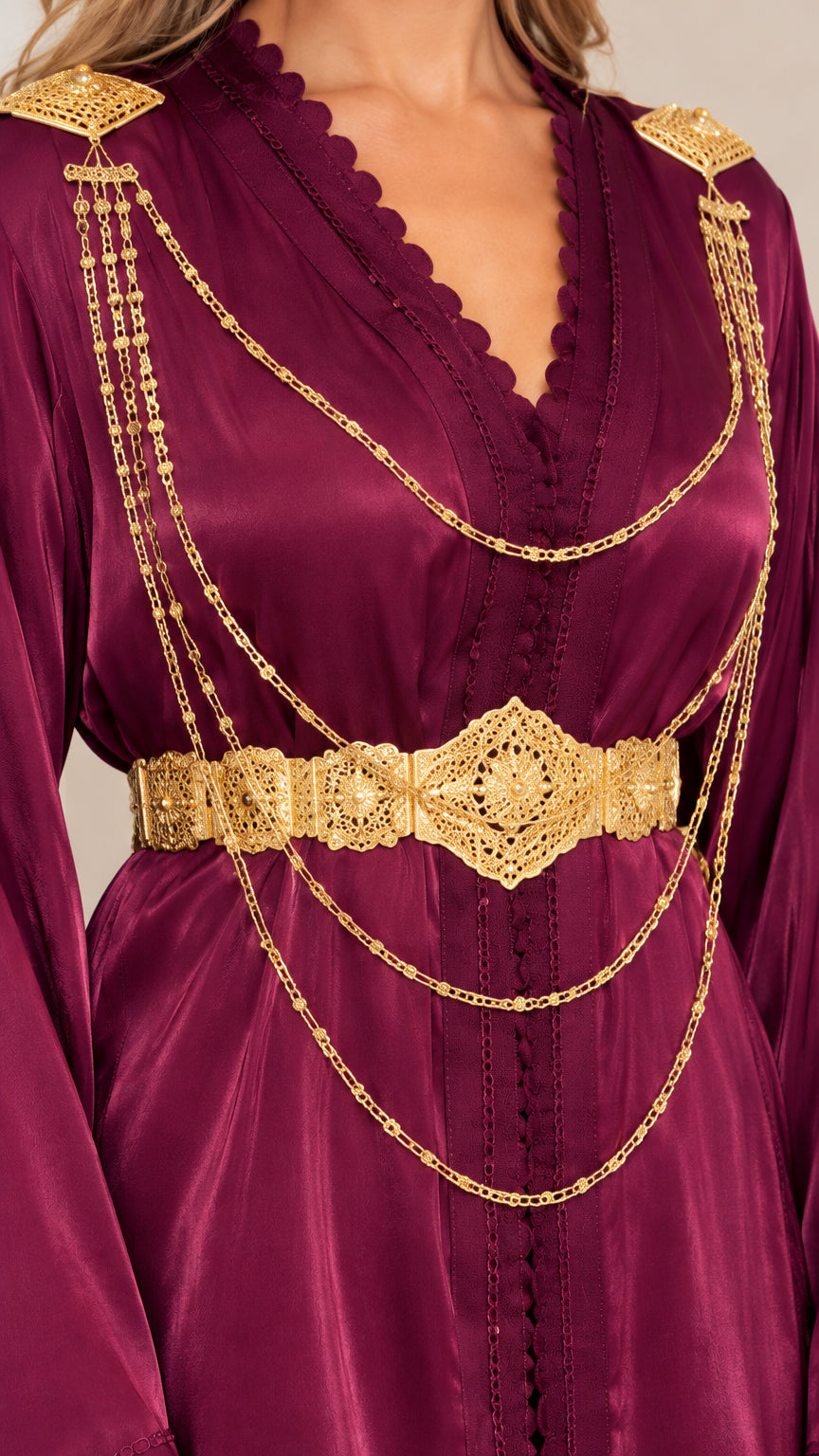 Close-up detail of ornate gold chain embellishment and scalloped neckline on burgundy satin gown
