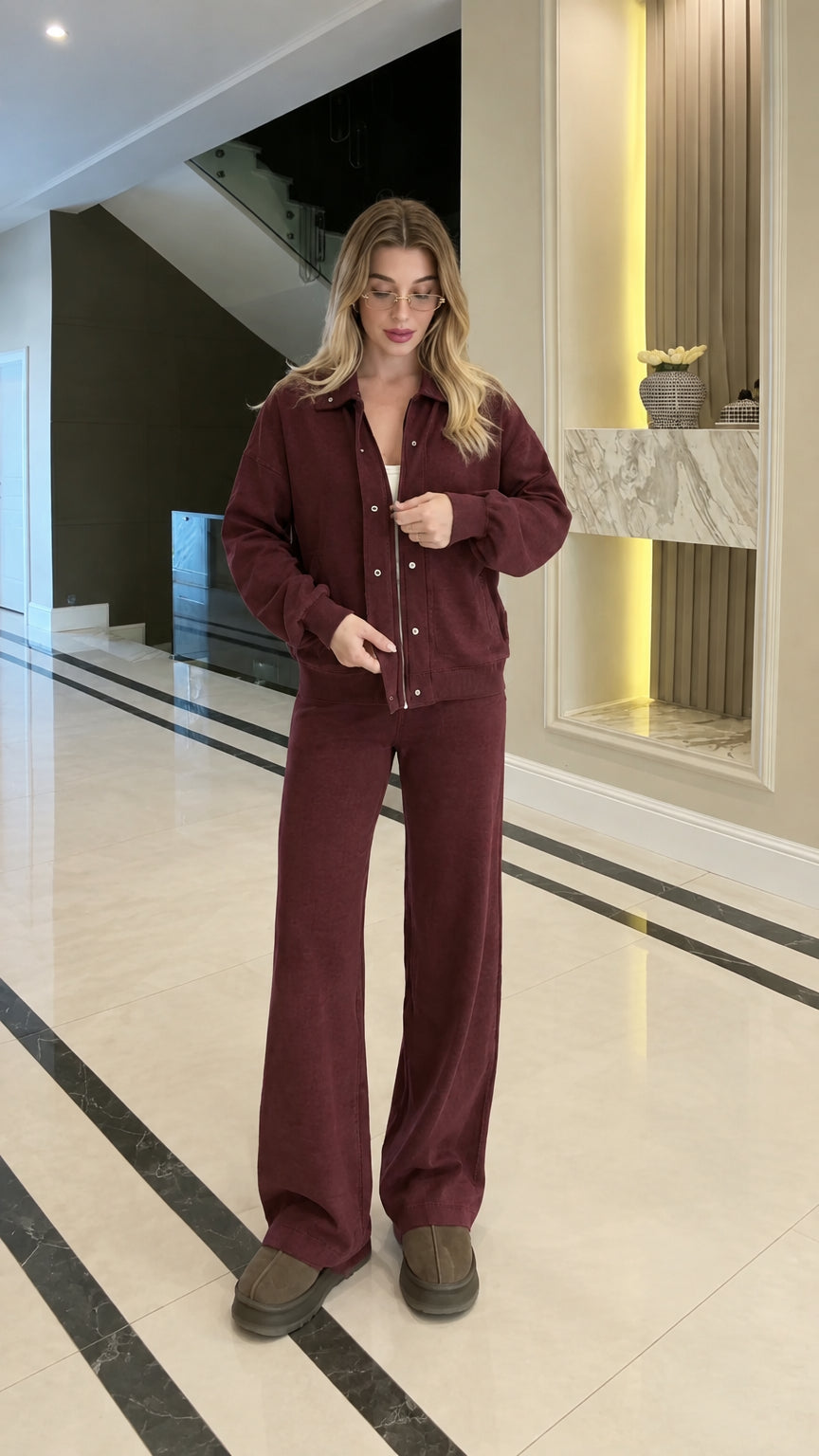 Full body studio shot of woman in burgundy collared zip-up jacket and wide-leg pants set