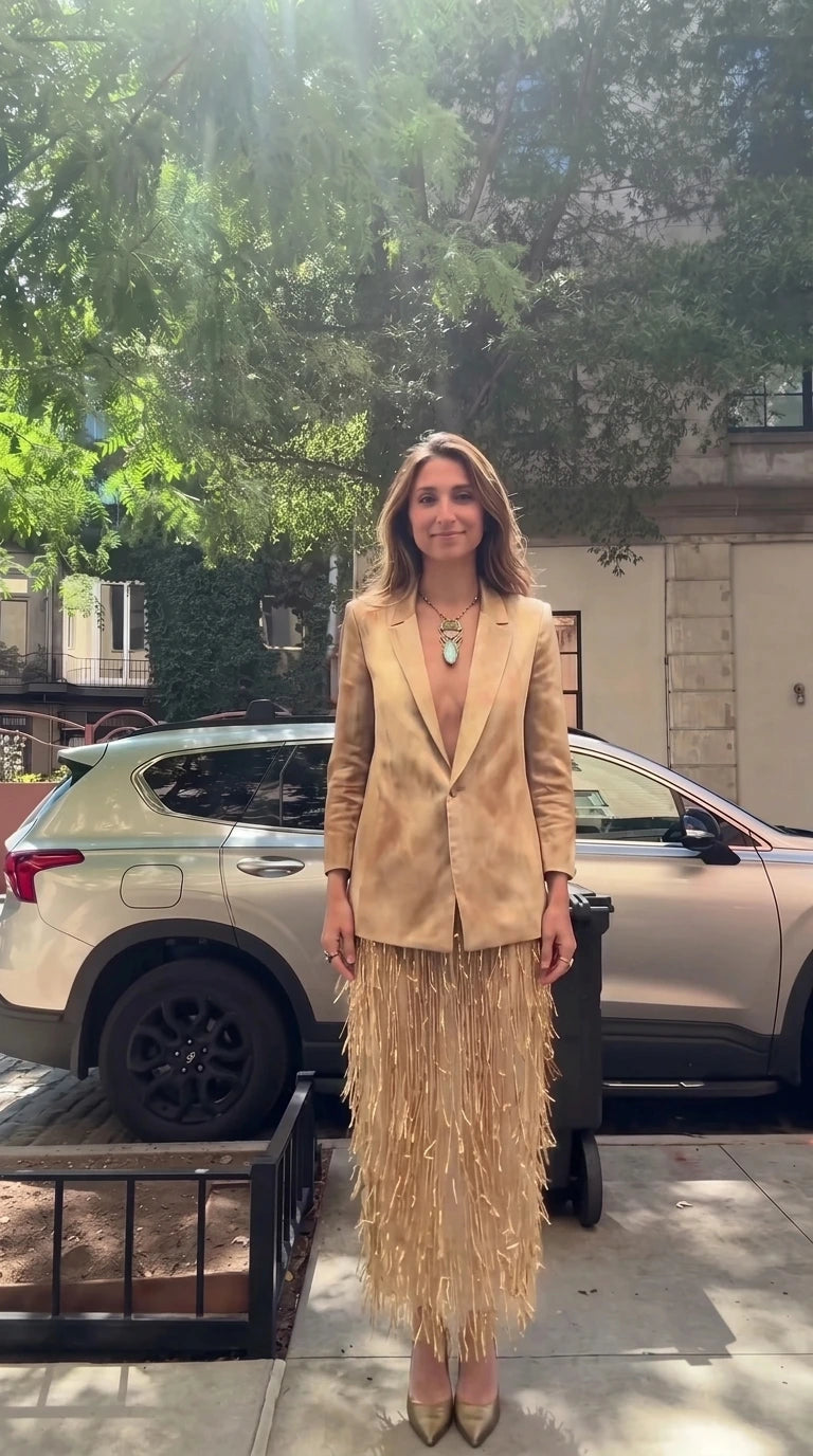 Model wearing champagne gold tailored blazer and matching golden fringe skirt set